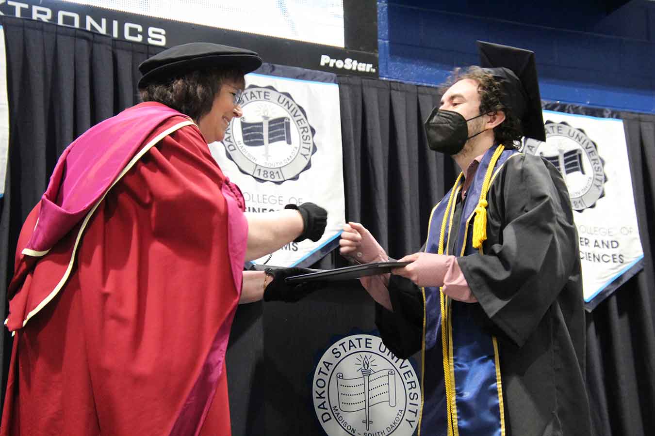 Odin Bernstein fist-bumps with President Griffiths as he receives his bachelor’s diploma in May 2021. 