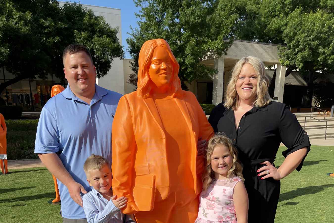 Dr. Ashley Podhradsky (right) poses with her family with her life-size statue,  which will be featured at the Smithsonian Institute in Washington, D.C. for Women’s Futures Month.