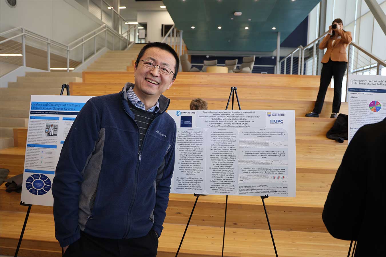 Dr. Peng Guo with a poster about his quantum physics research.