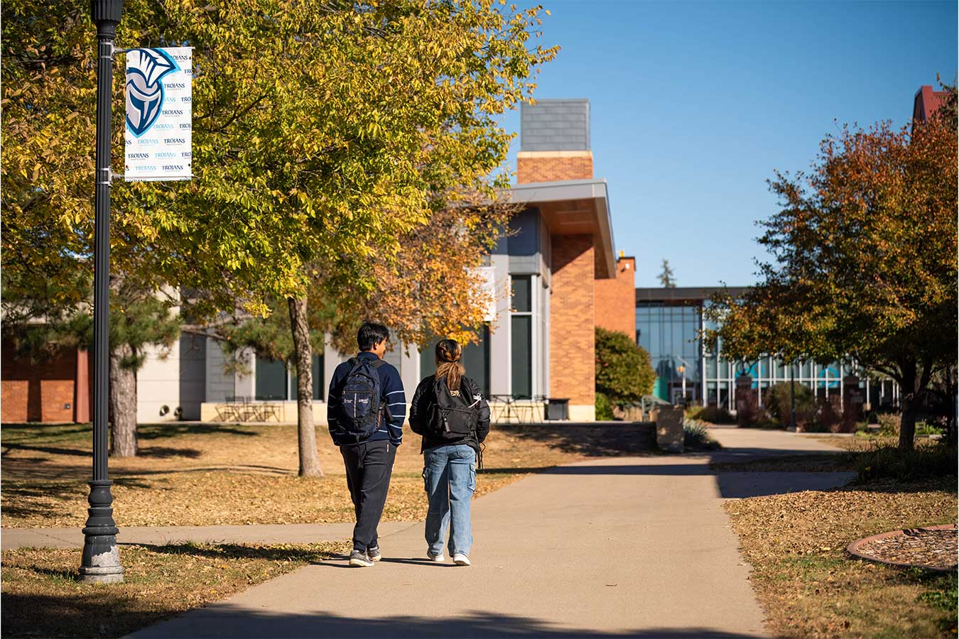 Two students walking on campus at Dakota State University in the fall.