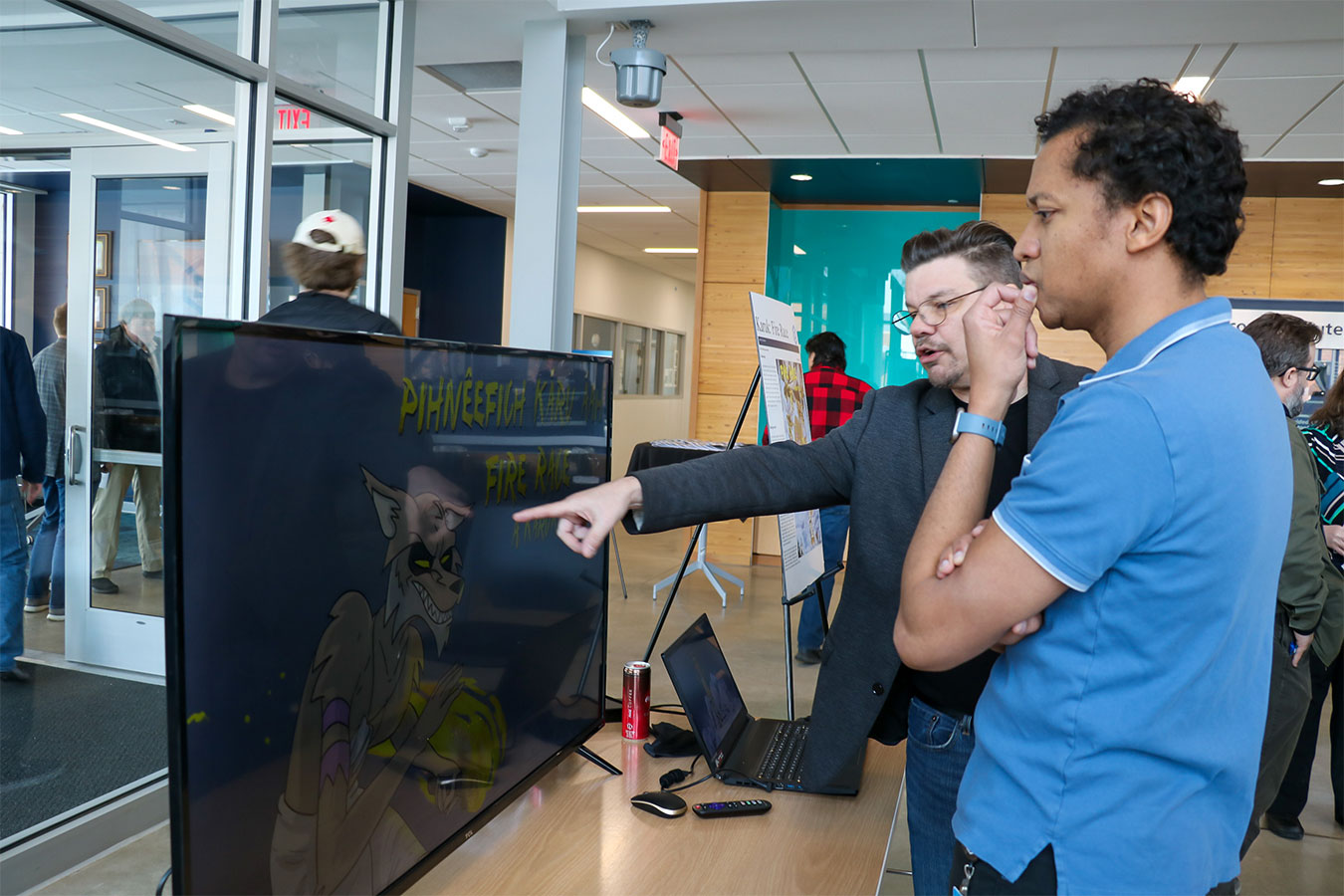 Daniel Welynn shows his work on Karuk Fire Race to another faculty member during a research symposium.