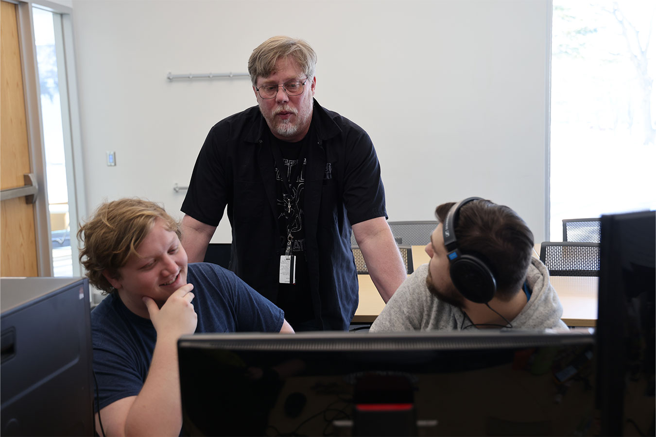 Assistant Professor Erik Pederson (standing) provides feedback to two students working on a game for Global Game Jam 2024. 