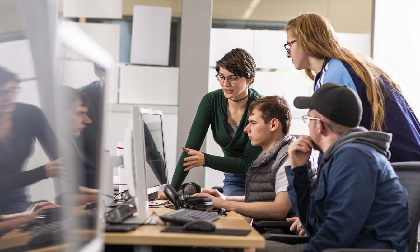 Students leaning over a computer screen analyzing results