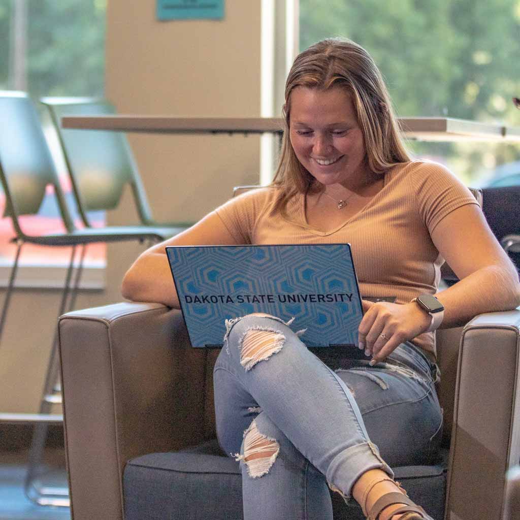 DSU student studying on a laptop in a residence hall common area