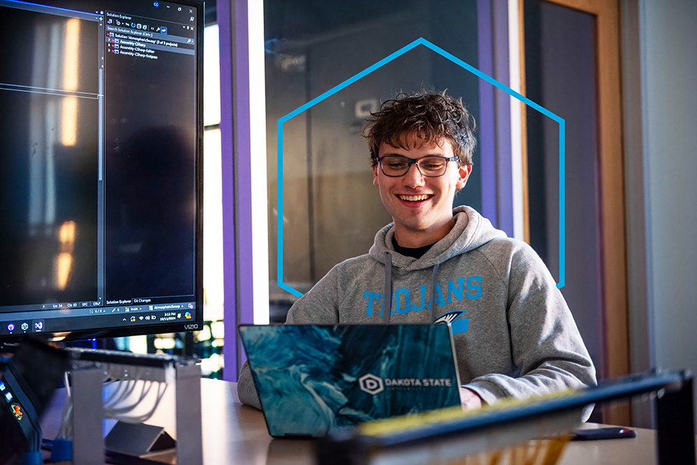 DSU student smiling at computer in class