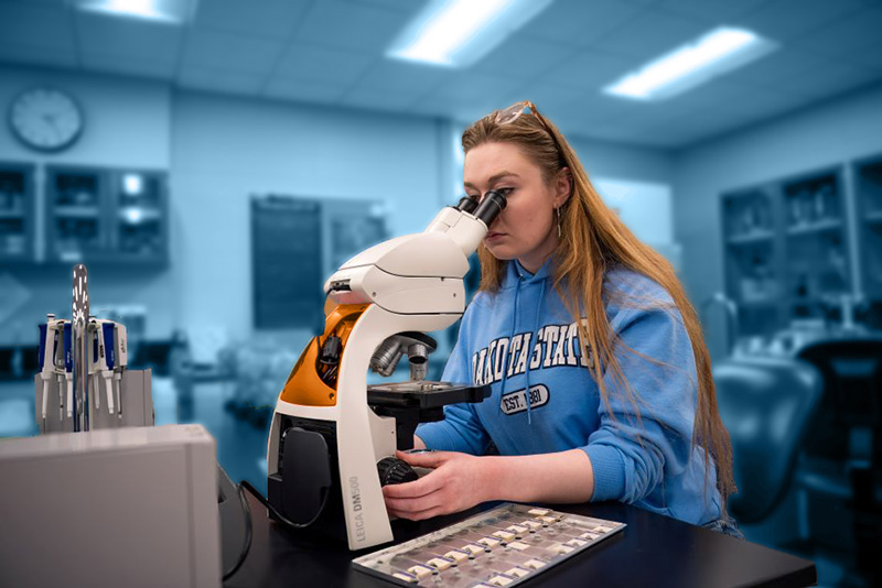 Student looking through microscope in lab