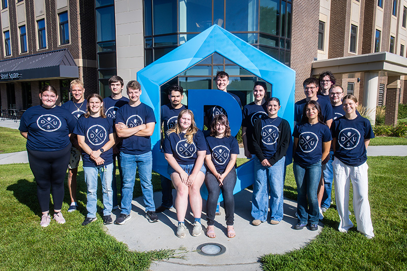DSU's student ambassadors posing around the Hex D sign on campus.