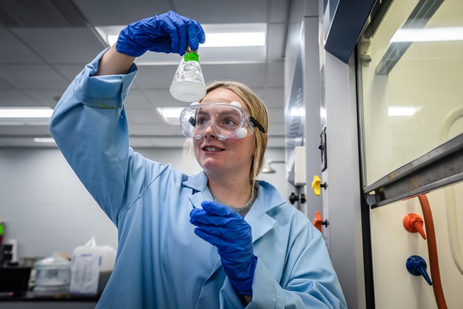 dsu student in biology lab looking at flask with goggles on