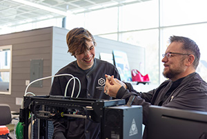 Dakota state faculty and graduate student working on a technical item.