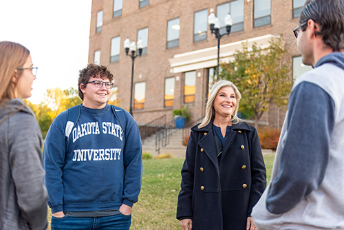 Dakota State University students and faculty chatting on university grounds.