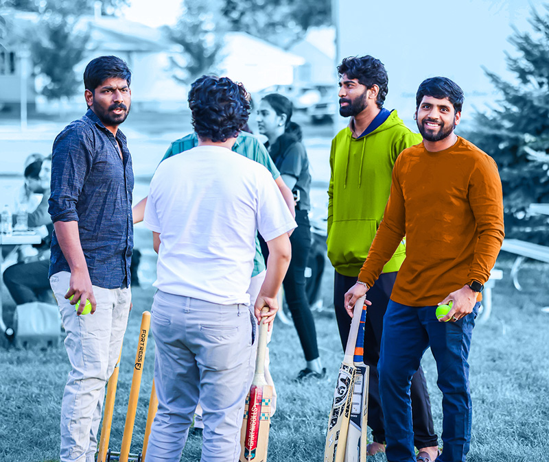 four international students standing holding cricket bats