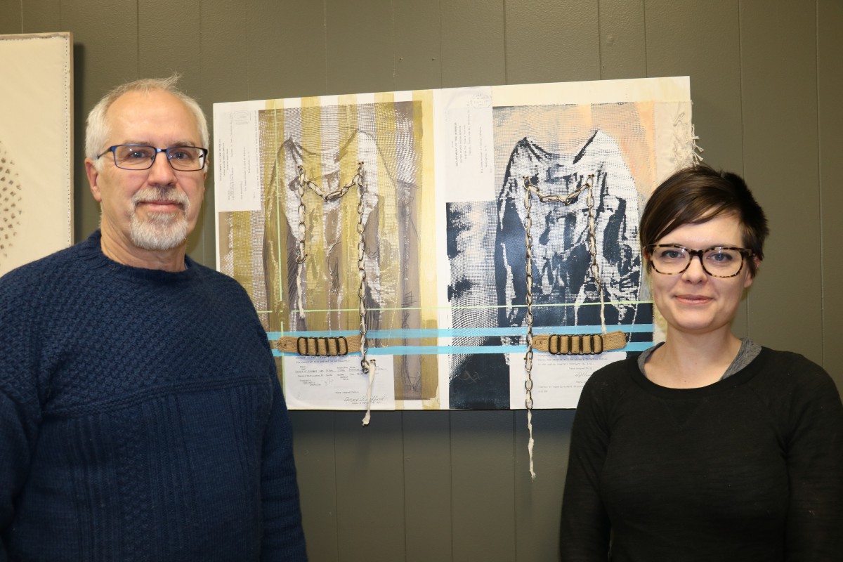 DSU English faculty Dr. John Nelson (left) and Dr. Stacey Berry pose by artwork inspired by the Hiawatha Indian Asylum. 