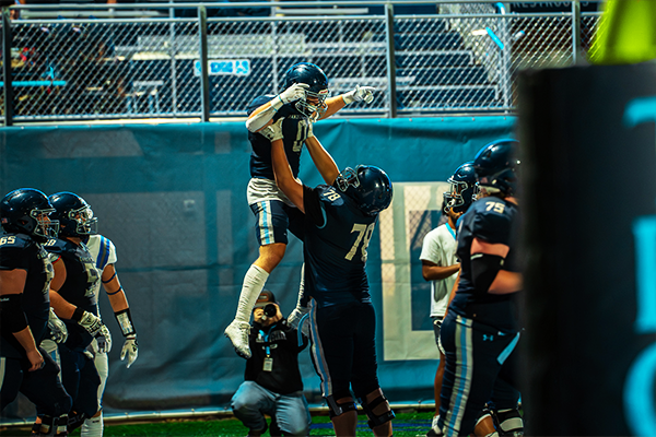 DSU trojan's football player lifting another in celebration
