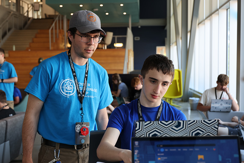 a camp counselor assisting a camper at their computer