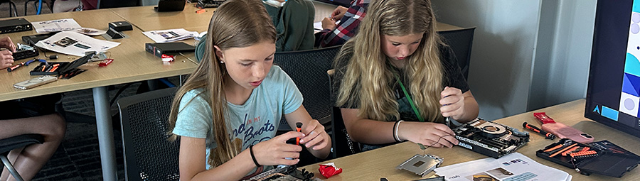 a group of middle school girls at a DSU cyber camp learning how to solder electronics