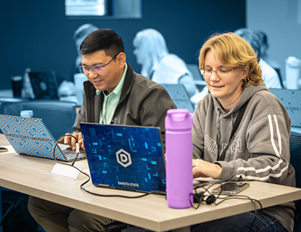 two teachers attending teacher camp with an open laptop in front of them