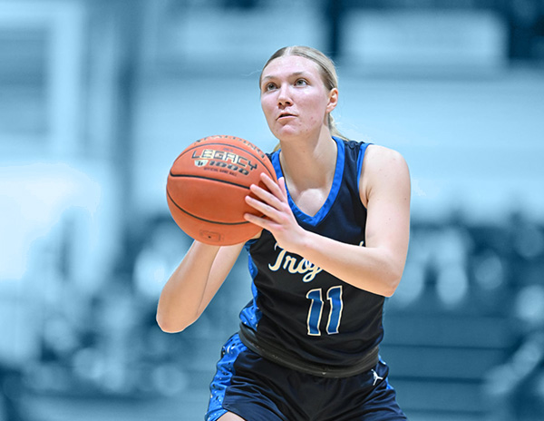 A young woman in a trojan's basketball jersey prepares to shoot a basketball.
