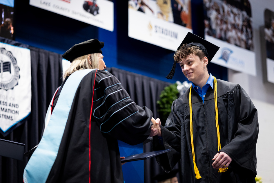 student receiving diploma shaking hands with provost