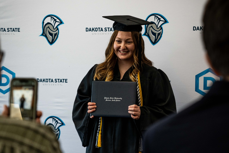 graduate posing with diploma