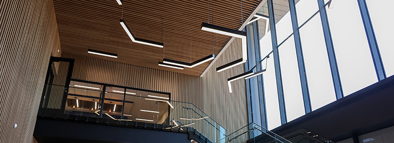 Light fixtures evoking the angles of DSU's hexagon hang from the high ceiling of the ARL building alongside high bright windows and an elegant balcony.