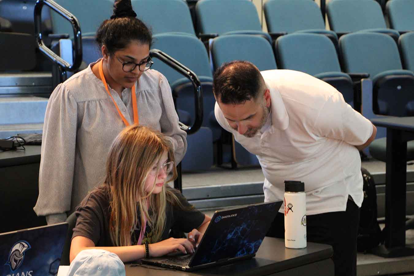 Justin Tolman (right), director of North American Training with AccessData, an Exterro company, answers a question for a young camper at the 2021 DSU GenCyber Camp, while camp director Kanthi Narukonda looks on. This camp session focuses on the importance of making wise decisions online.