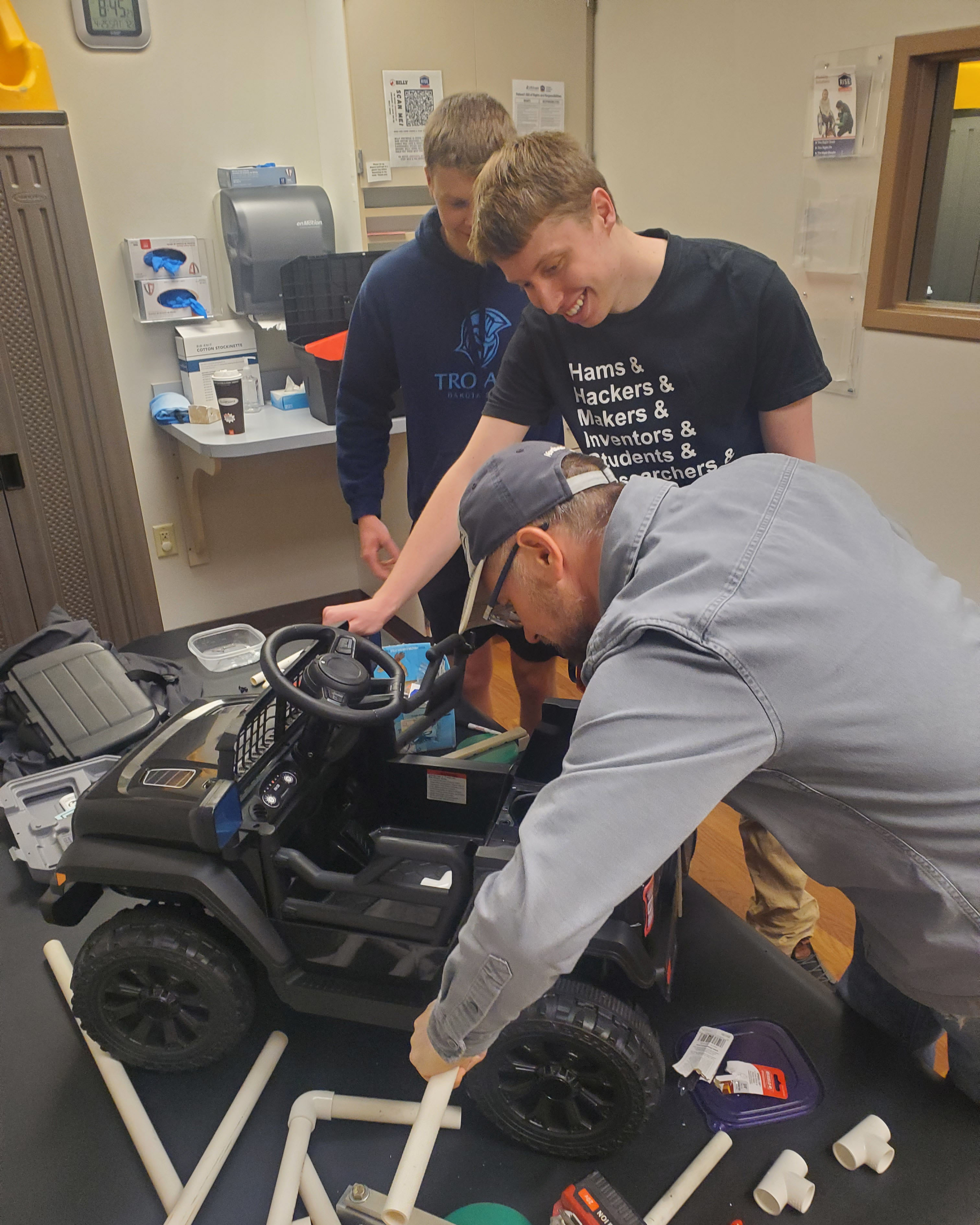 Adam Zimmel, Josiah Copeland, and Justin Blessinger work on Go Baby Go! vehicle