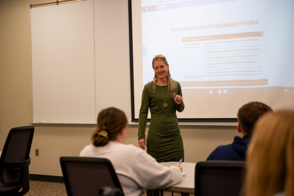 Dr. Kindra Schneider teaching in front of white board display