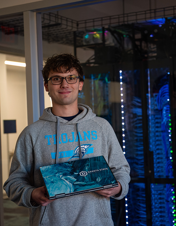 DSU student holding a laptop in a server room