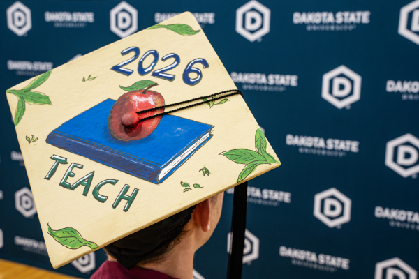 Graduate cap with 2026 teach and a photo of an apple and a book