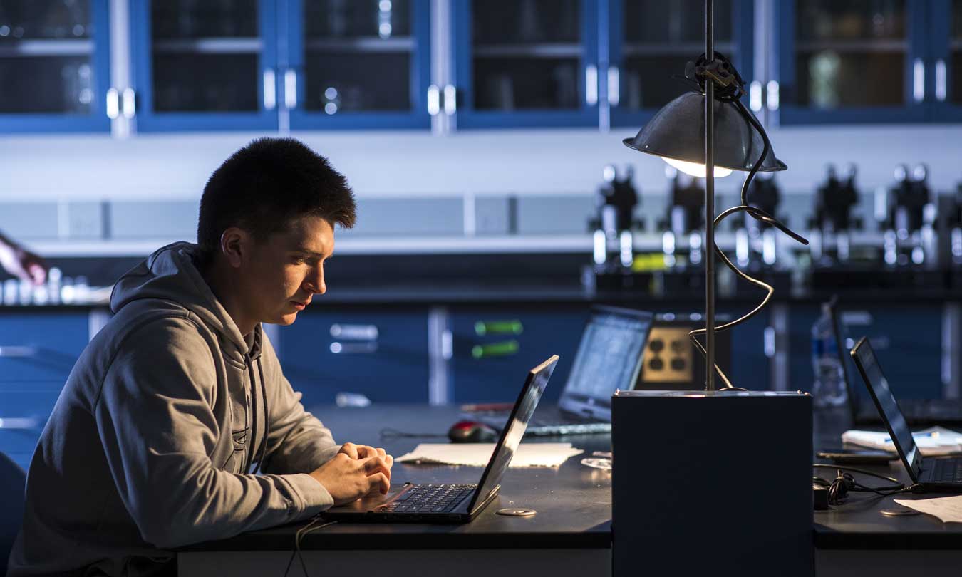 DSU Cyber Security student working at at desk at night