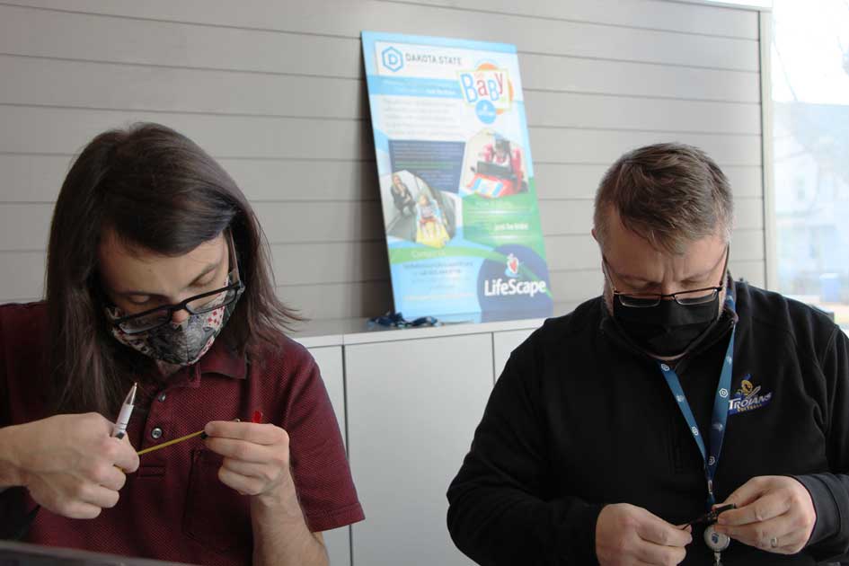 Mark Eisenbraun (left) and Dr. Justin Blessinger work on parts for a modified electric car presented to a South Dakota child. 