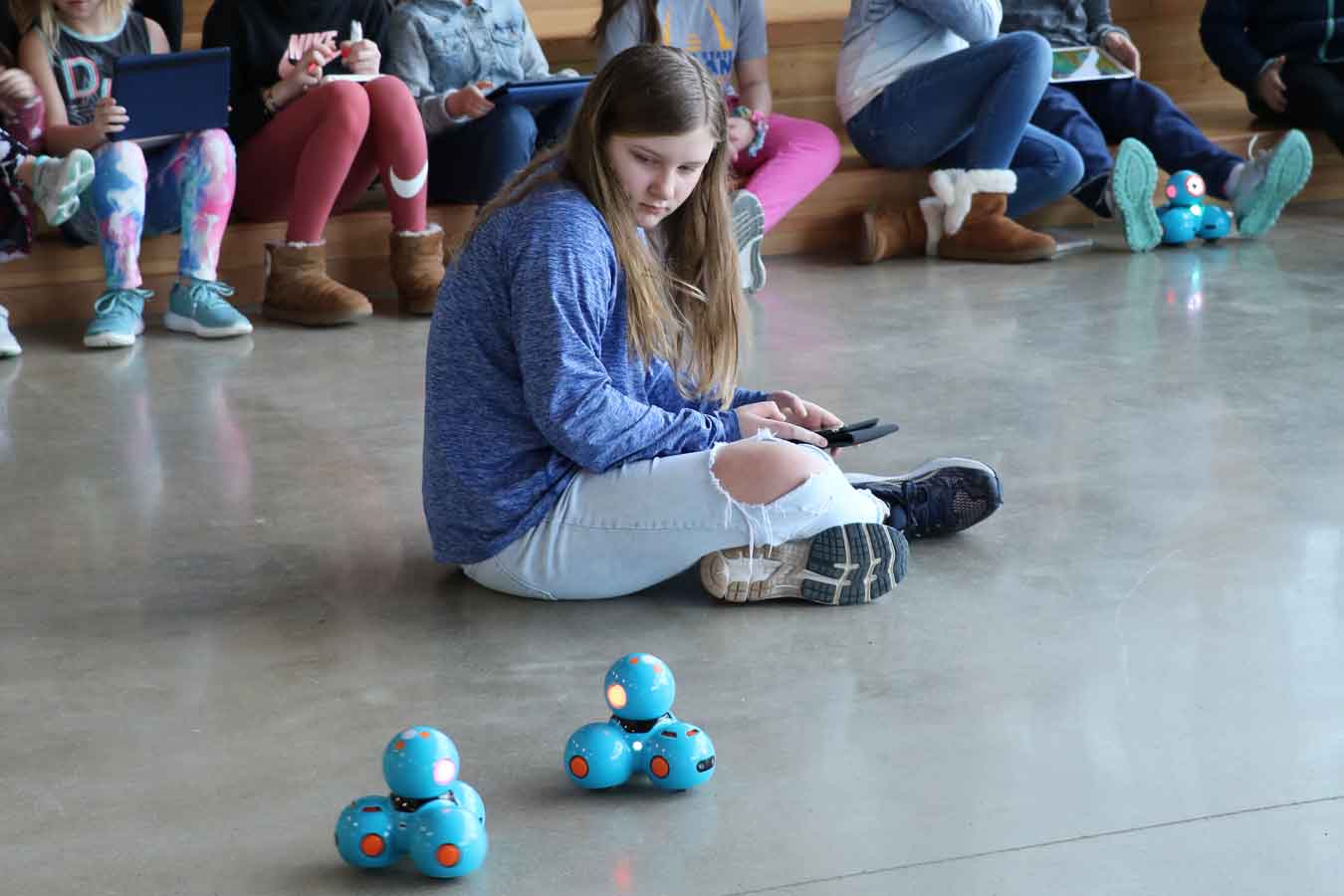 Young student engaged with robots at a CybHer event