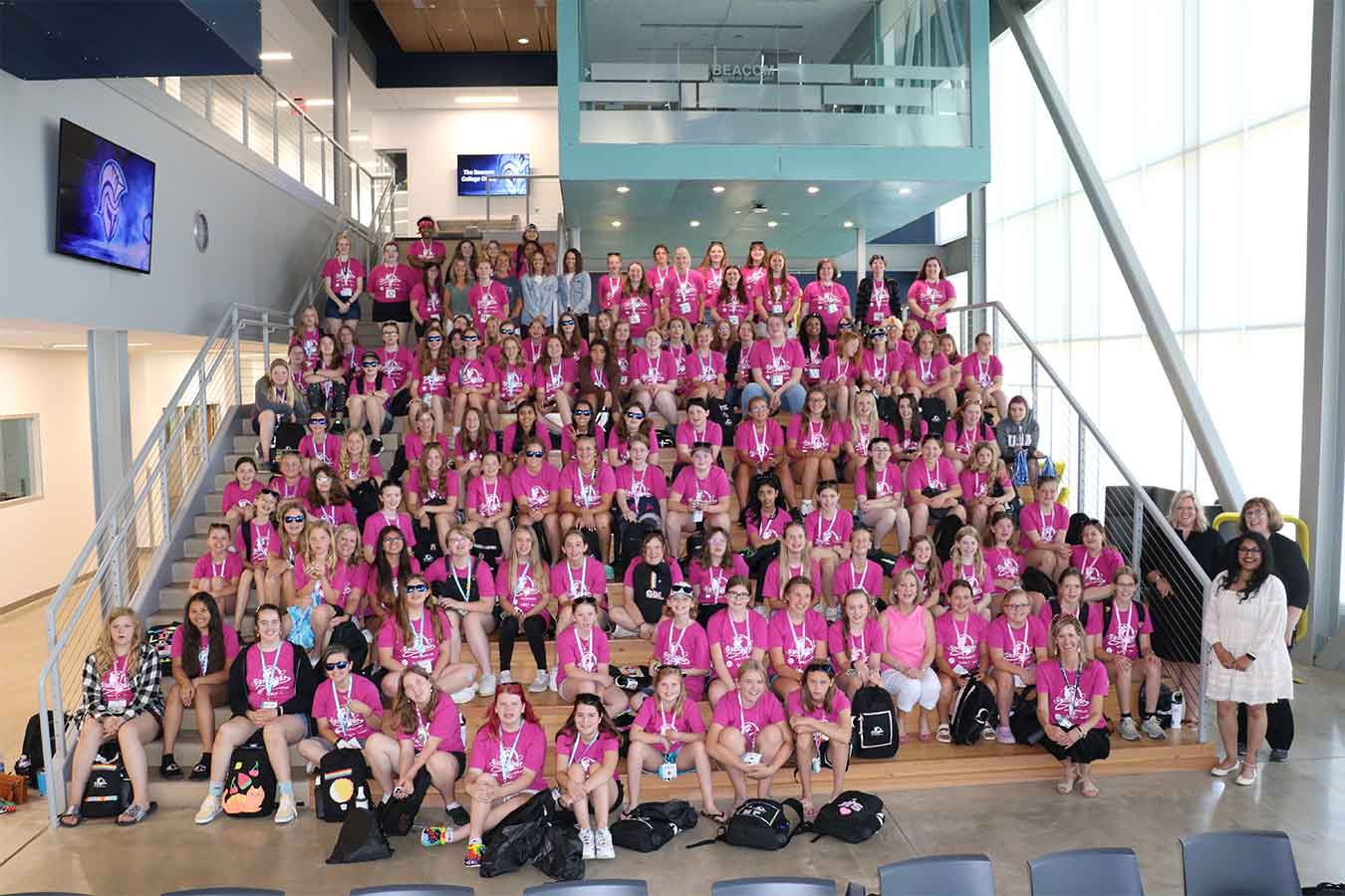A group photo of the CybHER summer camp attendees from the summer of 2022 sitting on the stairs of The Beacom Institute of Technology.