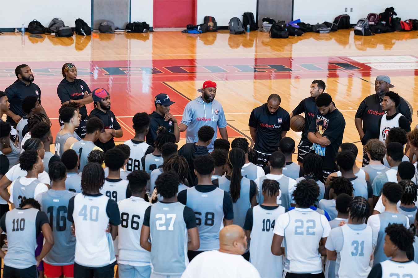 Braderious Martin  (pictured center wearing a grey short-sleeve hoodie and red hat talks to basketball players.