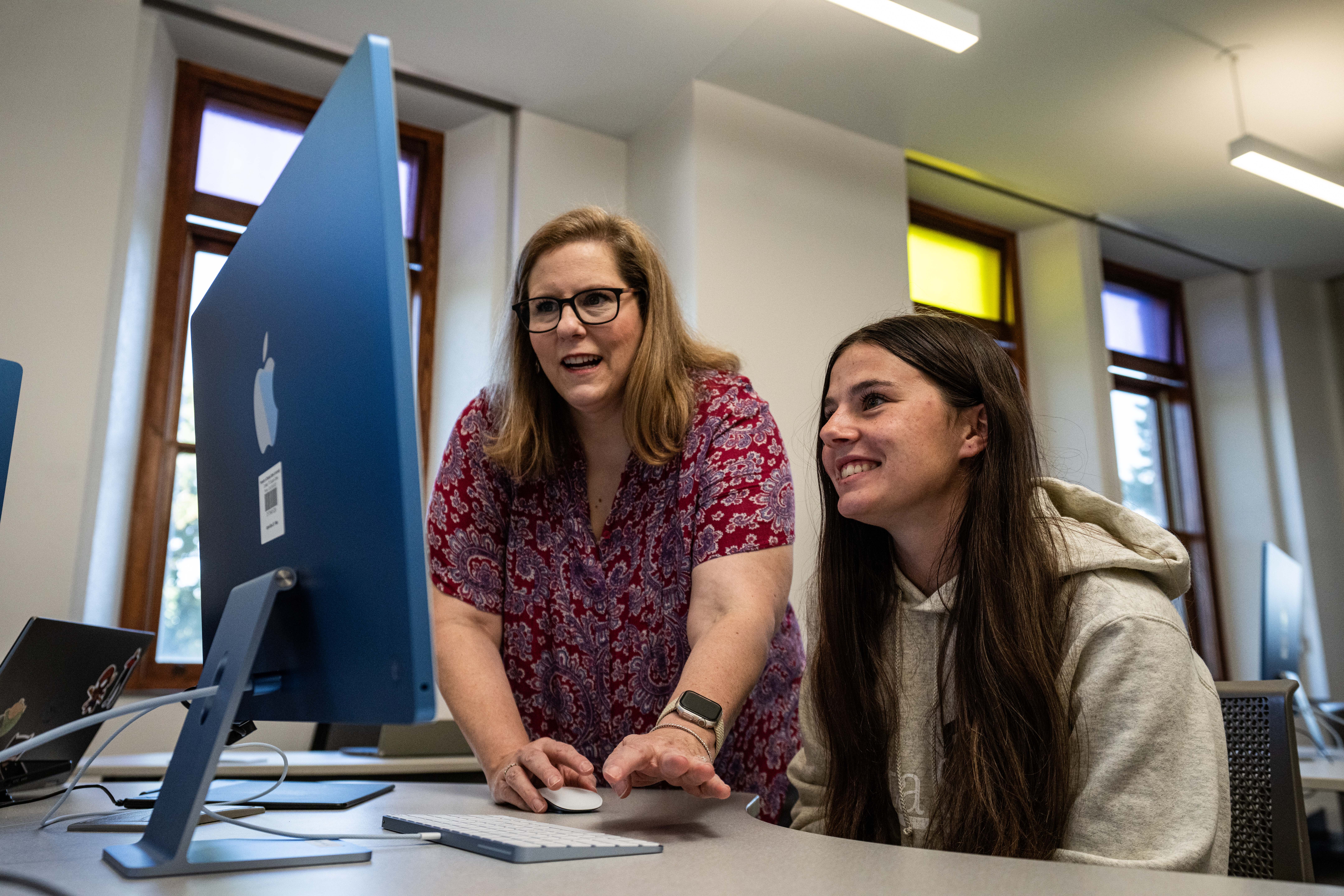 DSU associate professor Wendy Romero works with student on computer