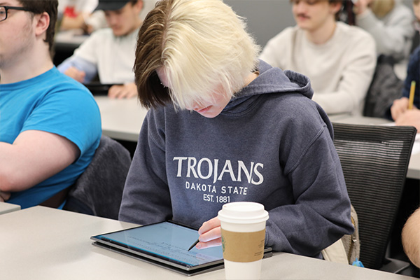 student taking notes on a tablet