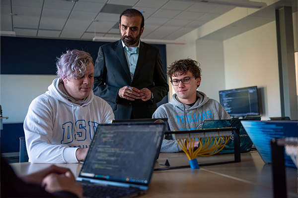 professor and students gathered around a laptop