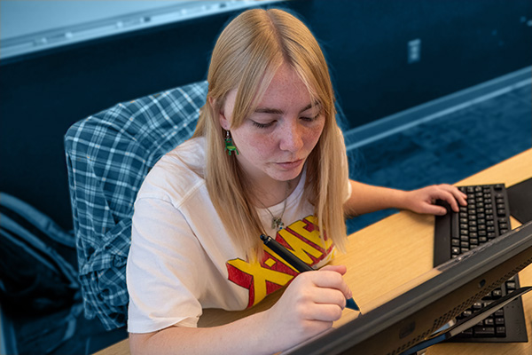 Digital arts and design student using a stylus to work on an electronic art tablet.