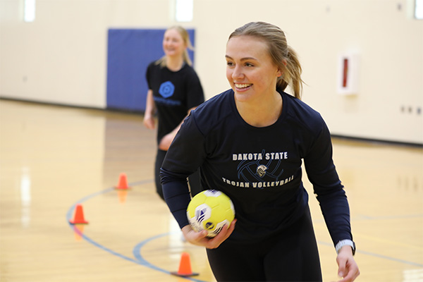 Student in a gym, smiling holding a handball