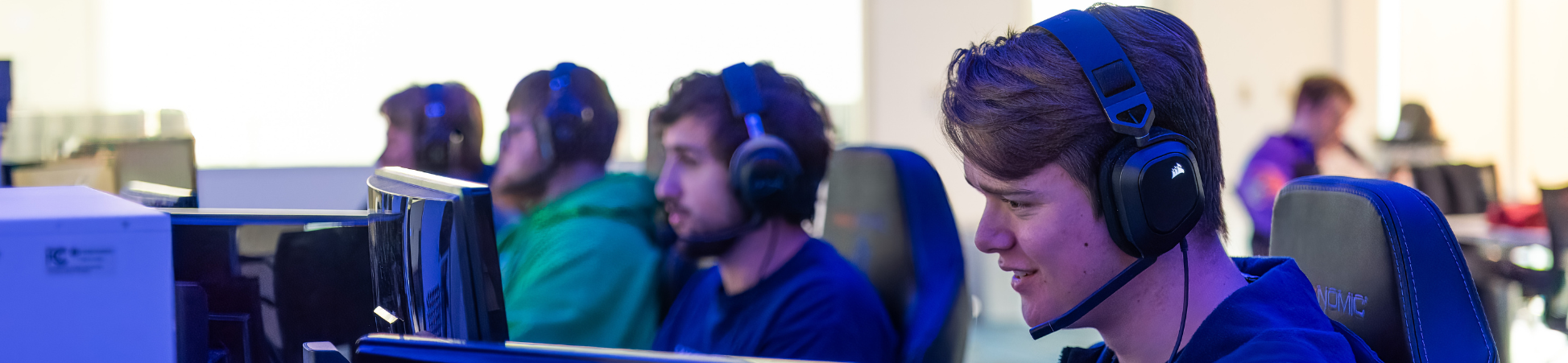 dsu students in esports room in beacom premier complex with headsets on and on computers
