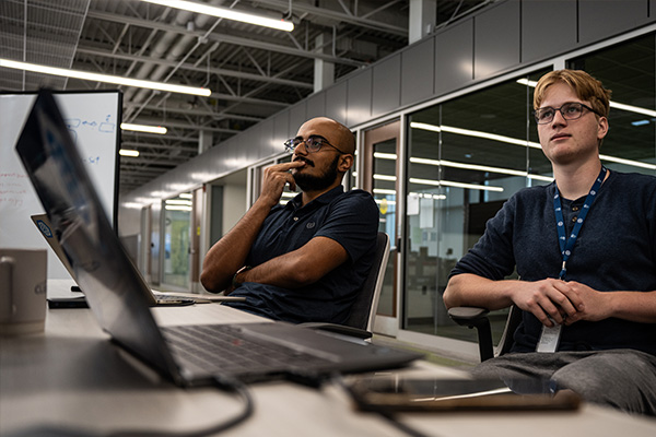 Two students sitting in madlabs paying attention to something off camera.