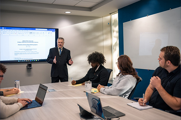 Business Management professor addressing a conference room of interested business students. 