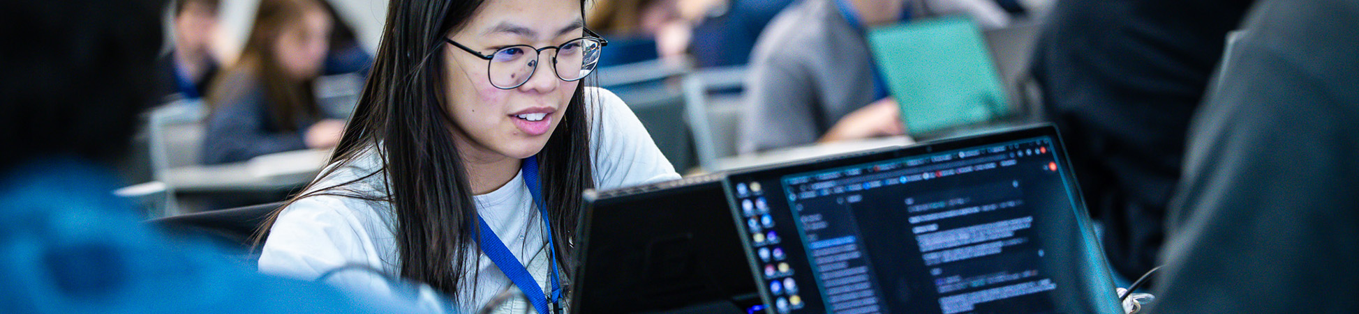 Students working on laptops with code on the screens. 