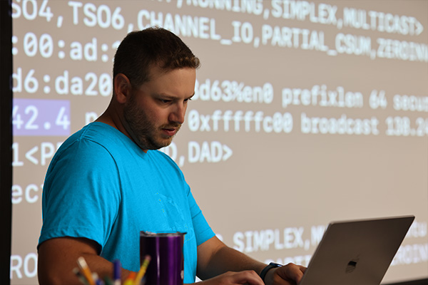 professor standing in front of a projection of code