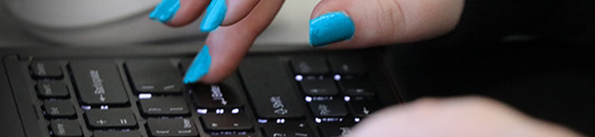 Hands with DSU blue colored fingernails typing on a keyboard