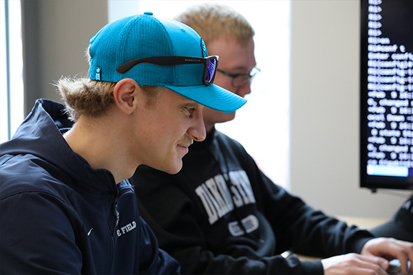 Creative Coding students in class in front of a screen of code. 