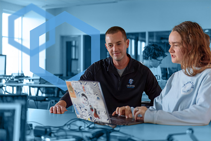 DSU student and DSU professor looking at classwork on computer in classroom.
