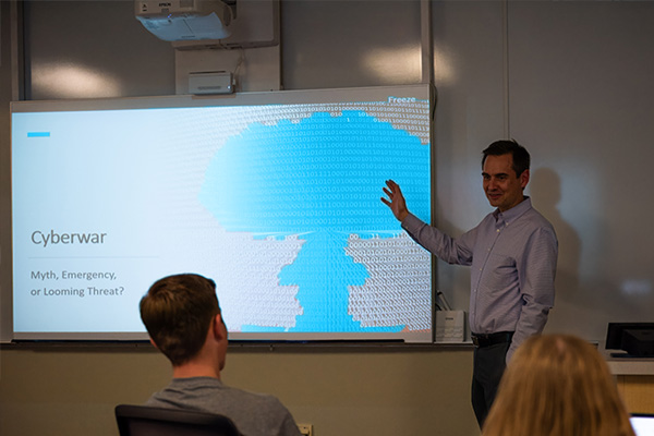 Cyber leadership professor in front of a presentation titled "Cyber War"