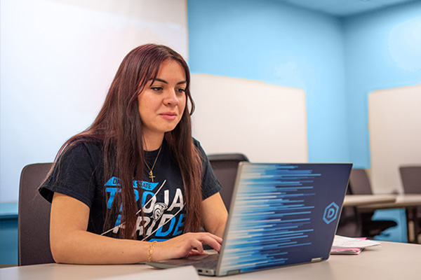 Cyber Leadership and intelligence student working on her laptop.