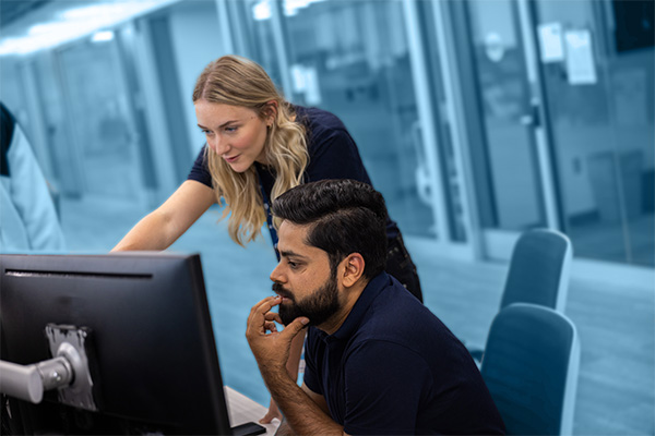 Cyber operations masters students collaborating at a desktop computer.